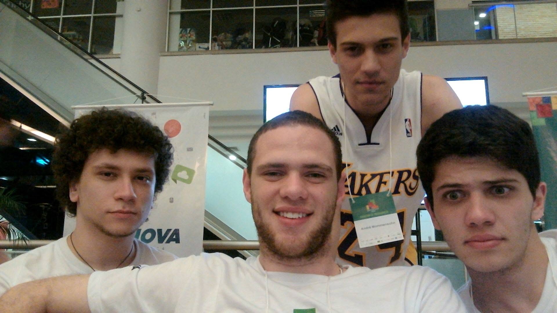Four friends posing for a selfie at a college hackathon, André in a Lakers jersey at the back