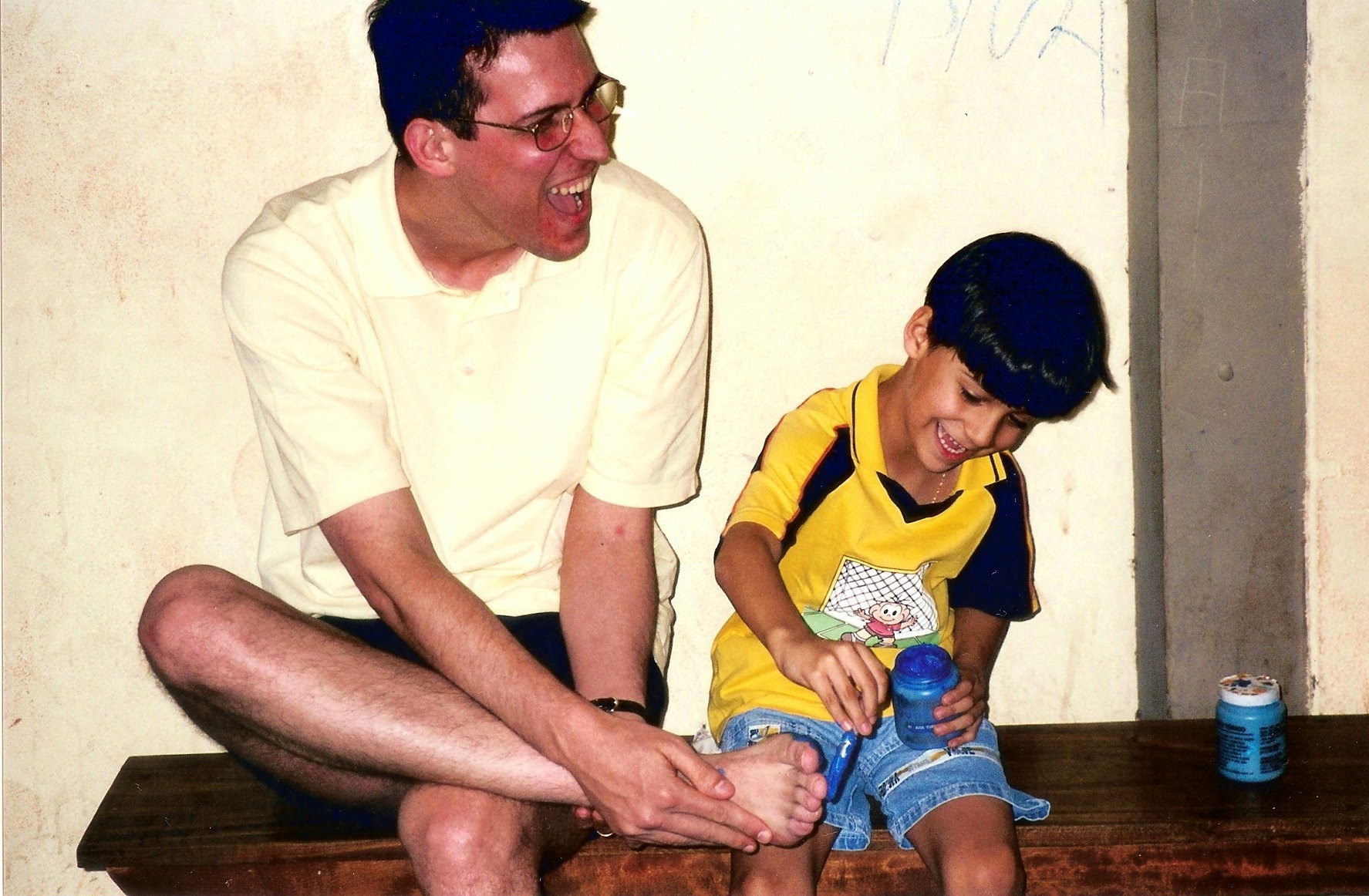 André as a kid laughing with his dad while painting on a bench