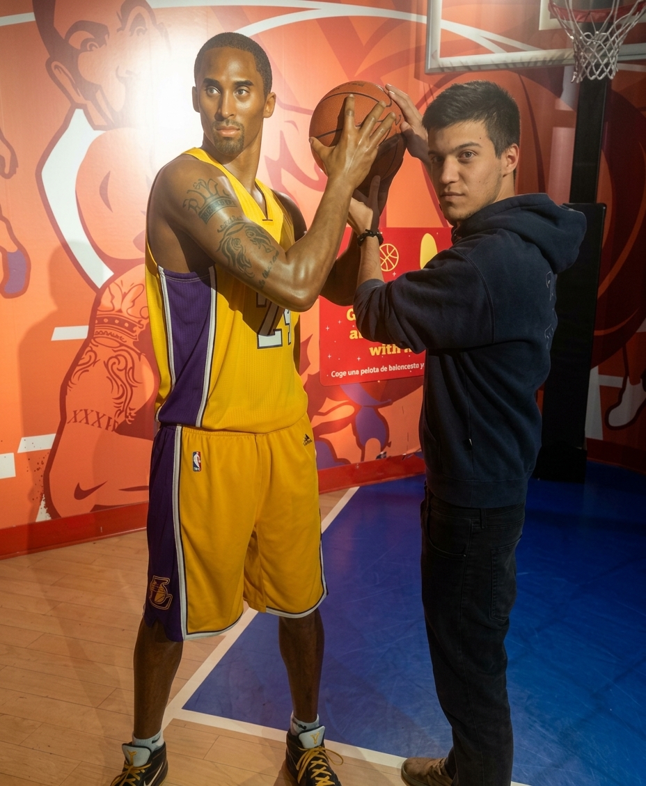 André posing with a wax figure of Kobe Bryant holding a basketball