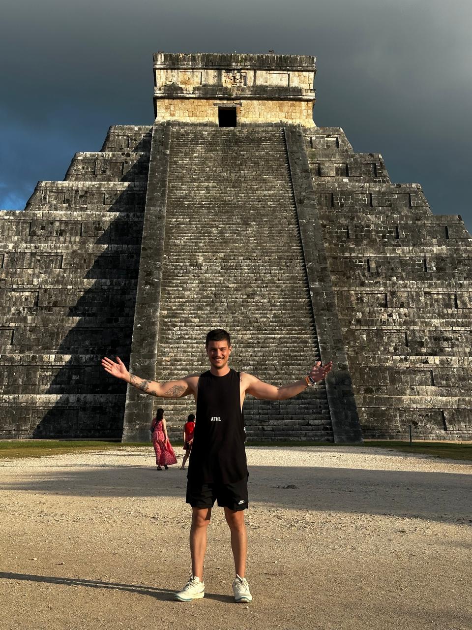André with open arms in front of the pyramid at Chichén Itzá
