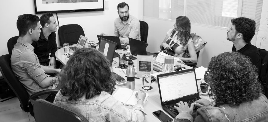 A team meeting around a table of laptops, in black and white